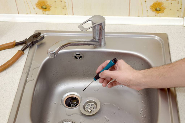 Gros plan de belles mains de plombier réparant le drain de l'évier de cuisine
 - Photo, image