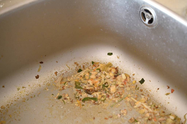 Закрыть на грязной засоряющей кухонной раковине слив с частицами пищи
 - Фото, изображение
