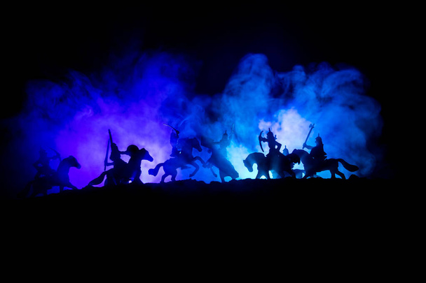 Средневековая боевая сцена с кавалерией и пехотой. Силуэты фигур как отдельные объекты, борьба между воинами на темном, тонированном туманном фоне со средневековым замком
. - Фото, изображение