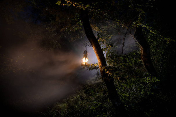Horror Halloween koncepcji. Spalanie starej lampy olejowej w lesie w nocy. Nocne dekoracje sceny koszmaru. - Zdjęcie, obraz