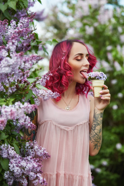 Fashion girl with bright red dyed hair in Apple and lilac flower - 写真・画像