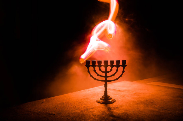 Low key image of jewish holiday Hanukkah background with menorah on dark toned foggy background - Photo, Image