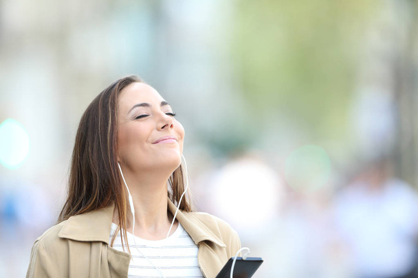 Femme satisfaite écoutant de la musique dans la rue
 - Photo, image