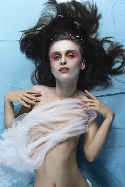 A beautiful naked girl with conceptual makeup in red tones is ly - Fotó, kép