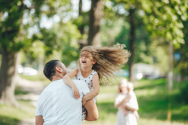 Padre e hija con hermoso pelo largo jugando en el verano en la naturaleza. Retrato familiar
 - Foto, Imagen