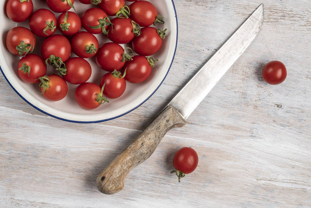 dojrzałe pomidory cherry i nóż na drewnianym stole - Zdjęcie, obraz