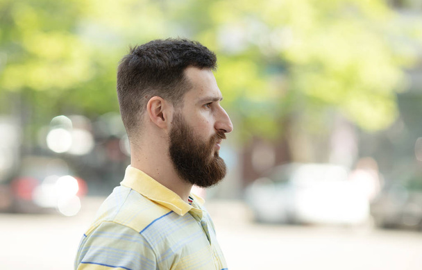 Young bearded man in striped t-shirt posing in park - Foto, Bild