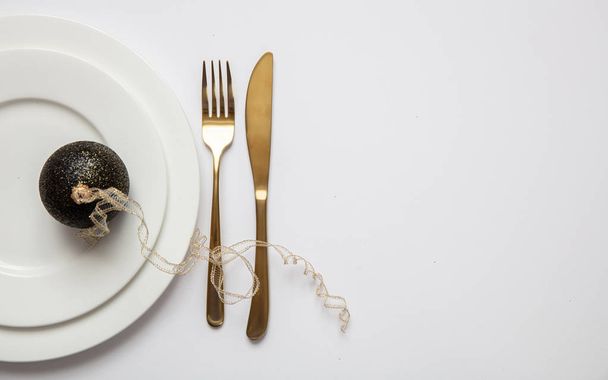 Ajuste de mesa, Navidad, año nuevo. Cubertería de oro sobre juego de platos blancos, fondo blanco
 - Foto, Imagen