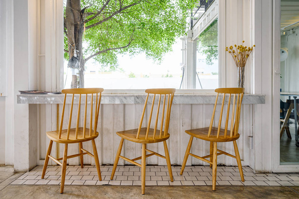 Wooden chairs with marble bar and tree on outside - Foto, Imagem