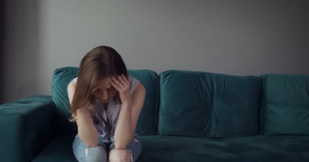 Young tired woman sits on sofa with a headache at home. - Záběry, video