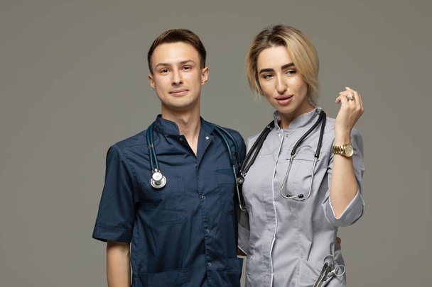 Happy Medical Workers. Portrait Of Two Doctors In White Coats Over Grey Background - Foto, imagen