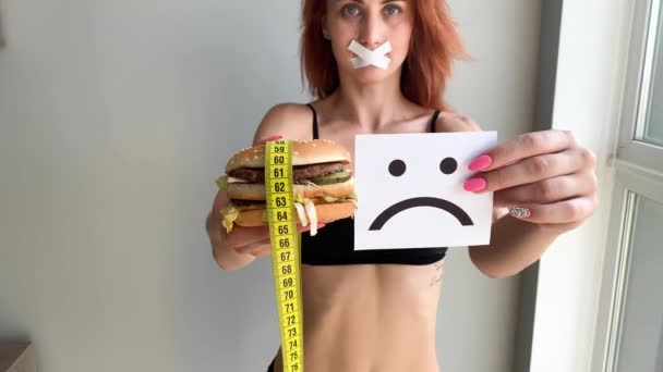 Régime alimentaire. Portrait d'une femme veut manger un hamburger, mais une bouche collée, une notion de régime alimentaire, des aliments malsains, une volonté dans la nutrition
 - Séquence, vidéo