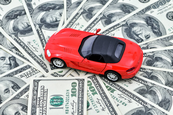 Concept-Toy rode auto en een pot geld dollar rekeningen. Goede tijd om een auto te kopen op krediet, sparen voor een voertuig. - Foto, afbeelding