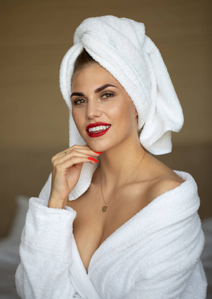 Portrait of blonde woman with bright makeup in bathrobe posing in hotel room - Foto, Imagem
