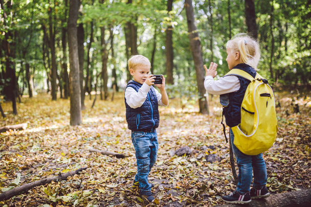 Kinder im Vorschulalter fotografieren sich gegenseitig mit der Handykamera im Waldparkherbst. Thema Hobby und aktiver Lebensstil für Kinder. Beruf Fotograf - Foto, Bild