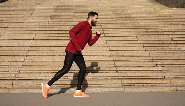 Young bearded man in sportswear running on stairs background - Photo, image