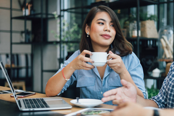 Aasialainen nainen sinisessä paidassa kahvilassa juo kahvia ja puhuu w
 - Valokuva, kuva