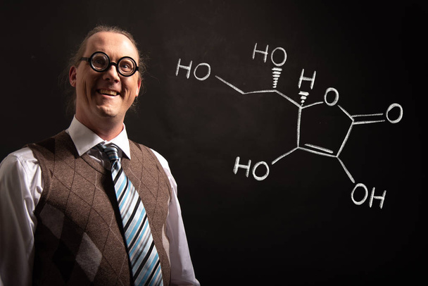 Profesor presentando fórmula química dibujada a mano de la vitamina C
 - Foto, imagen