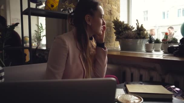 Happy Businesswoman Talking On The Phone. Woman In Cafe, use mobile Phone, Working On Notebook. Lady at cafeteria using phone and laptop, drink cup coffee. Pretty Businesswoman Working On Her Break - Footage, Video