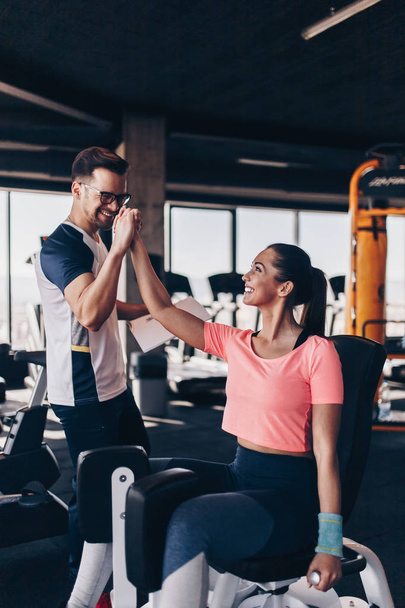 Young fit and attractive woman working out in modern gym together with her personal fitness instructor or coach. - Foto, Imagen