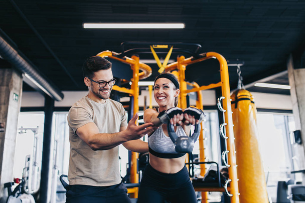Young fit and attractive man and woman exercising workout with kettlebell in modern fitness gym. - Valokuva, kuva