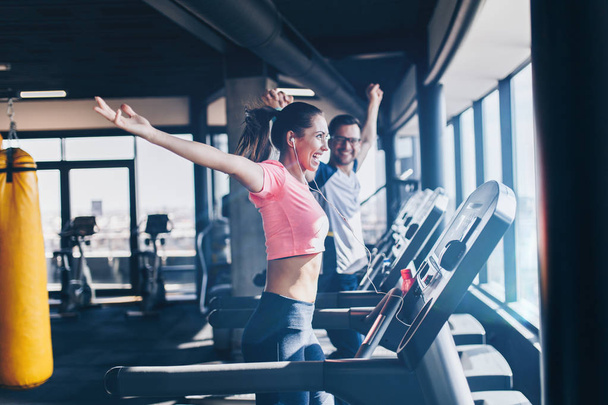 Young fit man and woman running on treadmill in modern fitness gym. - Foto, Imagen