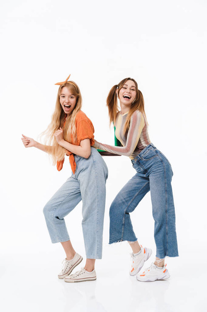 Full length photo of two cheerful girls wearing colorful clothes laughing and having fun together at camera - Фото, зображення