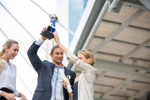 Equipo de empresarios con trofeo de oro en pie en la ciudad, o Empresario celebrando con trofeo el éxito en los negocios
 - Foto, imagen