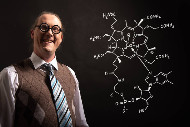 Profesor presentando fórmula química dibujada a mano de la vitamina B12
 - Foto, imagen