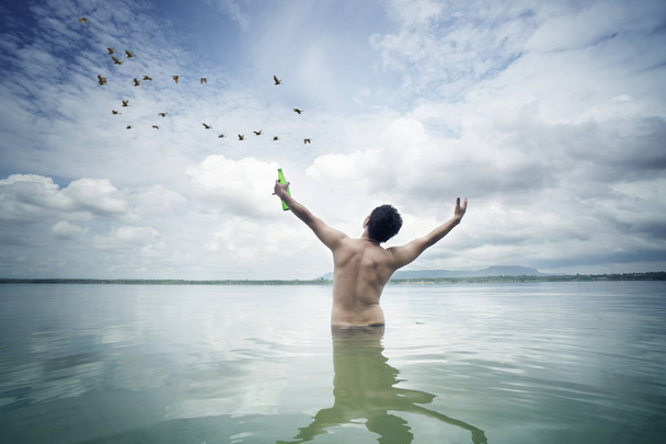 Щасливий чоловік насолоджується пивом і відкритою рукою в морі
 - Фото, зображення