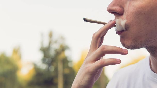 Genç kişi açık havada tıbbi marihuana ortak sigara. Y - Fotoğraf, Görsel