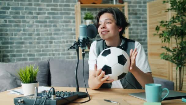 Joyful kid recording audio about football holding ball talking in microphone - Filmagem, Vídeo