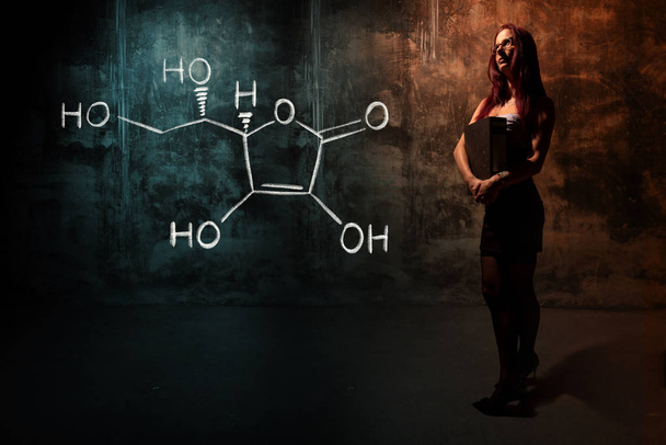 Сексуальная девушка или секретарь или студентка, представляющая химическую формулу витамина С, нарисованную вручную
 - Фото, изображение