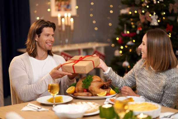 Красива пара ділиться подарунками під час різдвяної вечері
 - Фото, зображення