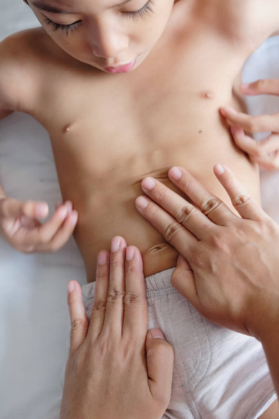 Criança fazendo massagem terapêutica em seu estômago para estímulo
 - Foto, Imagem