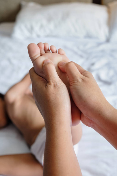 Мати дає дитині масаж ніг щоб стимулювати його зростання
  - Фото, зображення
