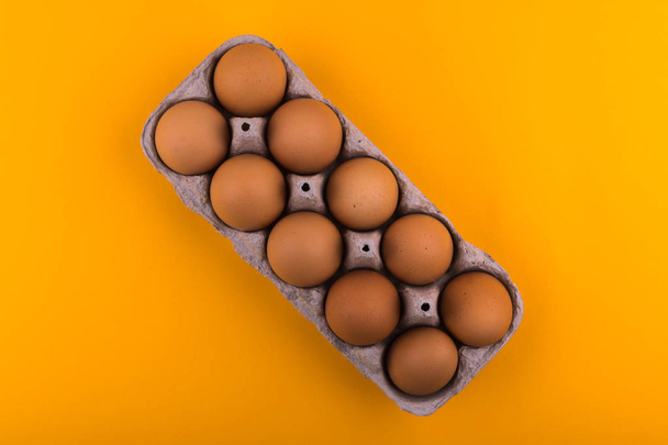 Hnědá Kuřecí vejce v podnosu leží na oranžovém pozadí - Fotografie, Obrázek