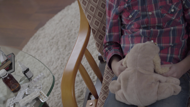 Neznámý chlapec houpající se v křesle, drží měkkou hračku, stůl s pilulkami, video - Záběry, video