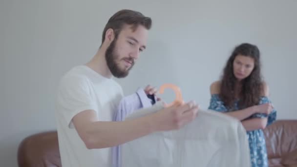 video, handsome bearded man asking wife advice shirts, preparing clothes  - Imágenes, Vídeo