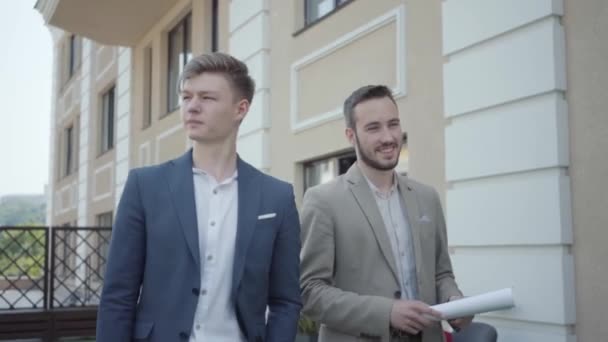 Portrait two confident men in formal wear walking on terrace discussing new project, video  - Felvétel, videó