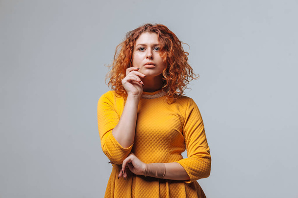 Redhaired curly girl Thinks on a light gray background - Foto, immagini