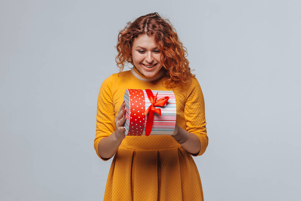 Рыжая девушка открыла подарочную коробку.
. - Фото, изображение