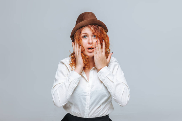Redheaded girl in brown hat and white shirt surprised - Fotografie, Obrázek