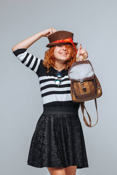 red head tourist girl with backpack on grey background - Фото, зображення