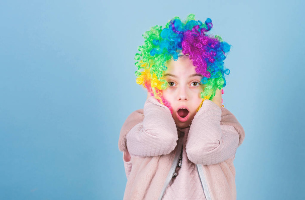 Wearing the foolish clown face. Surprised small clown with opened mouth. Adorable little girl wearing brightly colored clown hair wig. Everybody loves a clown, copy space - Zdjęcie, obraz