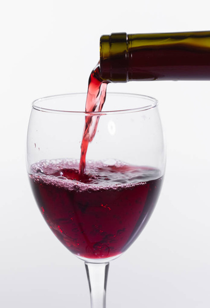 Pouring red wine into the glass on white background, close-up - Photo, Image
