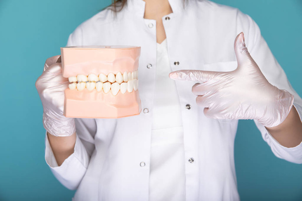 Zubař v rukavicích, který drží lékařské vybavení v modrém studiu. - Fotografie, Obrázek