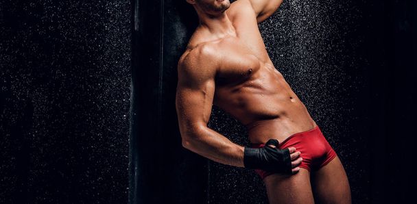 Καυτά μυώδης άνθρωπος με γυμνό κορμό και σάκο του μποξ - Φωτογραφία, εικόνα