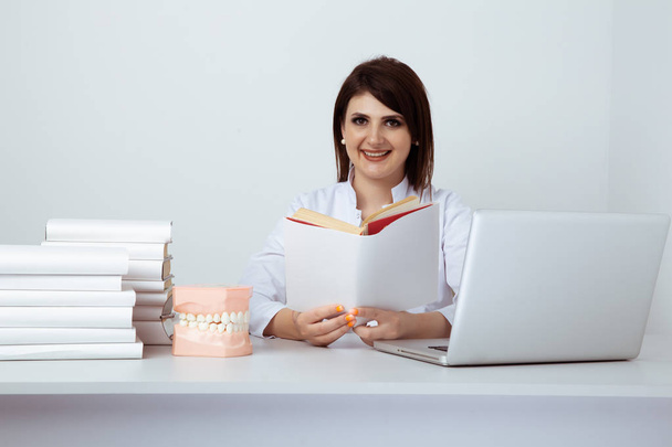 Kobieta dentysta w mundurze siedzi przy biurku i pracuje z dentystą w biurze. - Zdjęcie, obraz