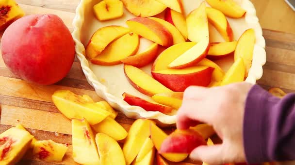 A woman fills a pie crust with fresh peach slices - Footage, Video